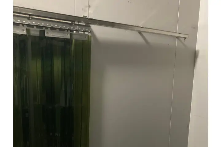 食品工場の冷蔵庫出入口に設置されたスライド式の防虫グリーンカーテン